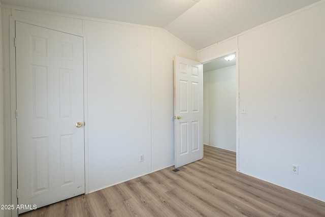 unfurnished bedroom with light wood-type flooring and lofted ceiling