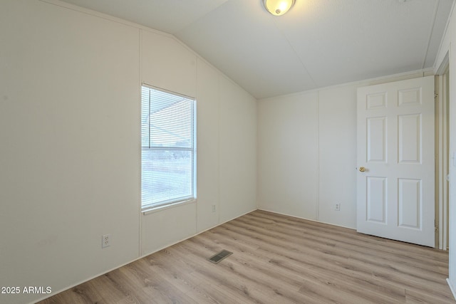 unfurnished room with light wood-type flooring and lofted ceiling