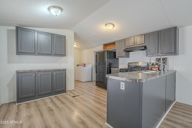 kitchen with black refrigerator, gray cabinetry, light hardwood / wood-style floors, kitchen peninsula, and stove