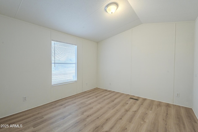 unfurnished room featuring vaulted ceiling and light hardwood / wood-style flooring