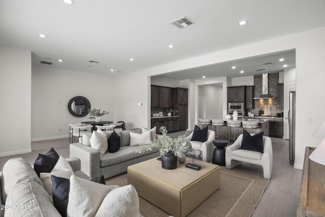 living room with baseboards, light wood-type flooring, visible vents, and recessed lighting