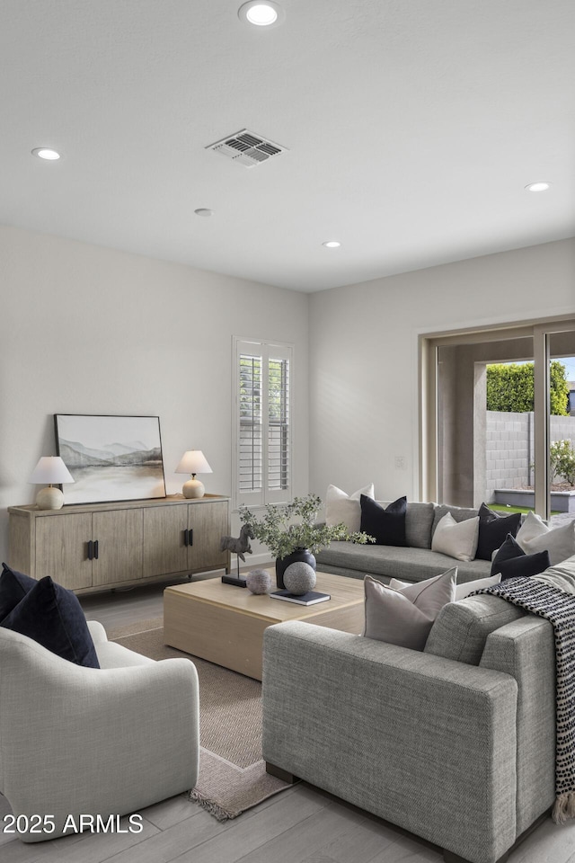 living room with recessed lighting, visible vents, and wood finished floors