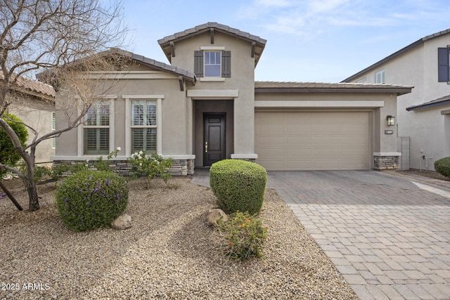 view of front of house featuring decorative driveway, stucco siding, an attached garage, stone siding, and a tiled roof