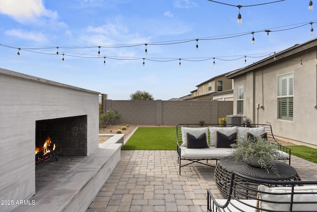 view of patio with an outdoor living space with a fireplace, a fenced backyard, and central AC