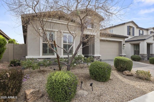 view of front of property featuring stone siding, fence, driveway, and stucco siding