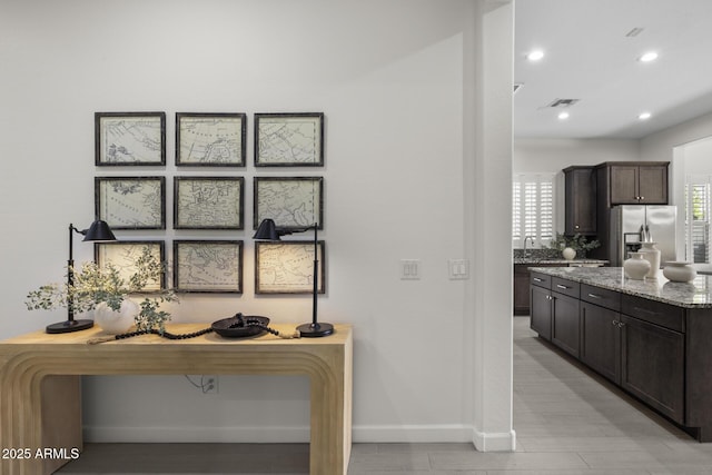 interior details with stainless steel fridge, baseboards, light stone countertops, light wood-style floors, and recessed lighting