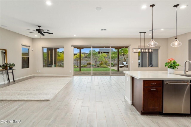 kitchen featuring ceiling fan, hanging light fixtures, sink, dishwasher, and light wood-type flooring