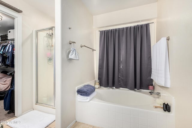 bathroom featuring a garden tub, a spacious closet, and a shower stall