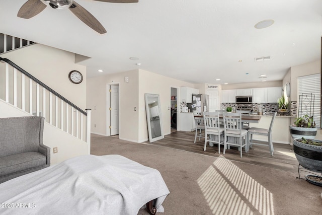 living area with recessed lighting, visible vents, light carpet, baseboards, and stairs