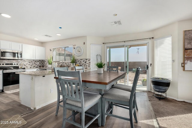 dining space featuring dark wood-type flooring, recessed lighting, visible vents, and baseboards