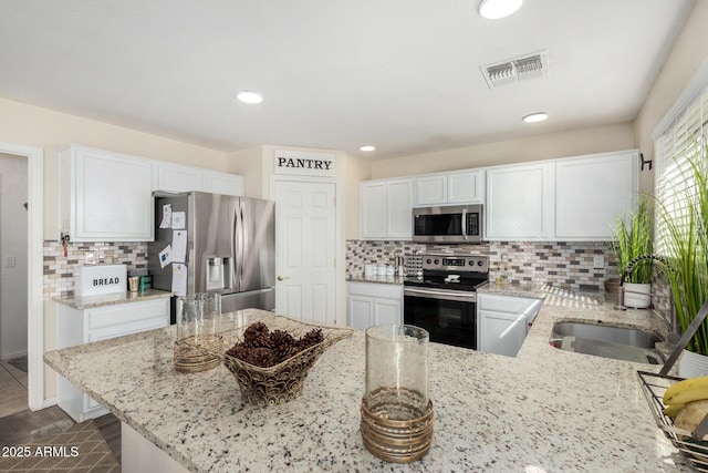 kitchen with visible vents, appliances with stainless steel finishes, light stone counters, and a sink