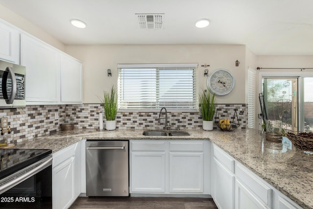 kitchen with visible vents, decorative backsplash, white cabinets, appliances with stainless steel finishes, and a sink