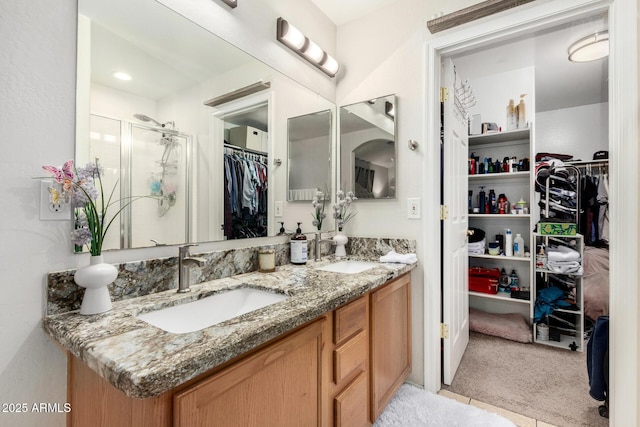 bathroom featuring double vanity, a sink, a walk in closet, and a shower stall