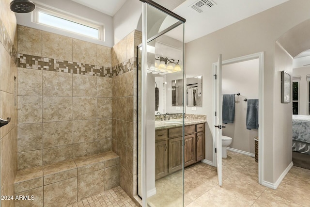 bathroom featuring tile patterned flooring, vanity, toilet, and tiled shower