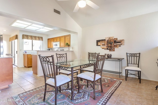 dining room with ceiling fan, light tile patterned flooring, and vaulted ceiling