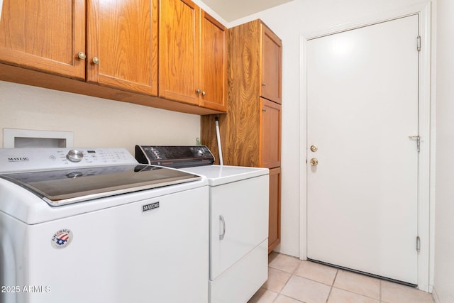 clothes washing area featuring cabinets, separate washer and dryer, and light tile patterned floors