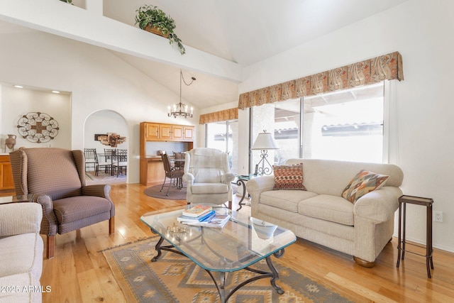 living room with an inviting chandelier, light hardwood / wood-style floors, and high vaulted ceiling