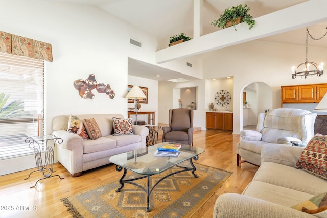 living room with high vaulted ceiling, light hardwood / wood-style flooring, and an inviting chandelier