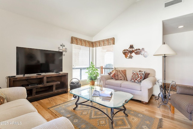 living room with light hardwood / wood-style floors and high vaulted ceiling