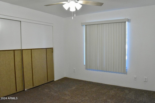 unfurnished bedroom featuring ceiling fan, a closet, and dark colored carpet