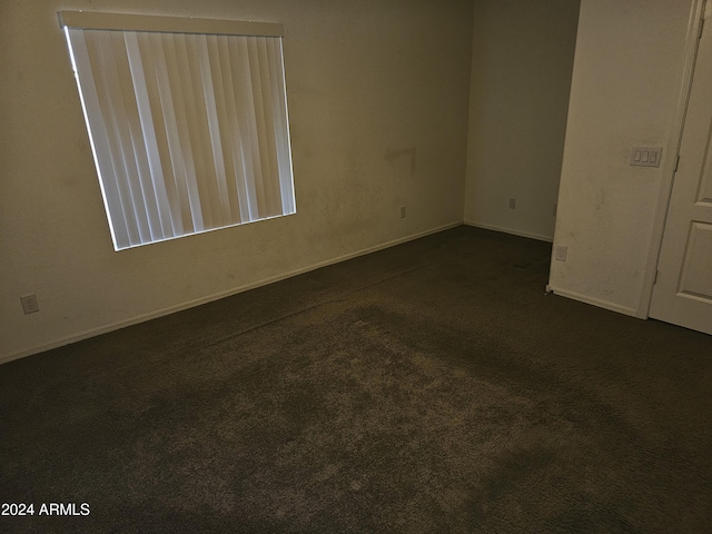 spare room featuring dark carpet