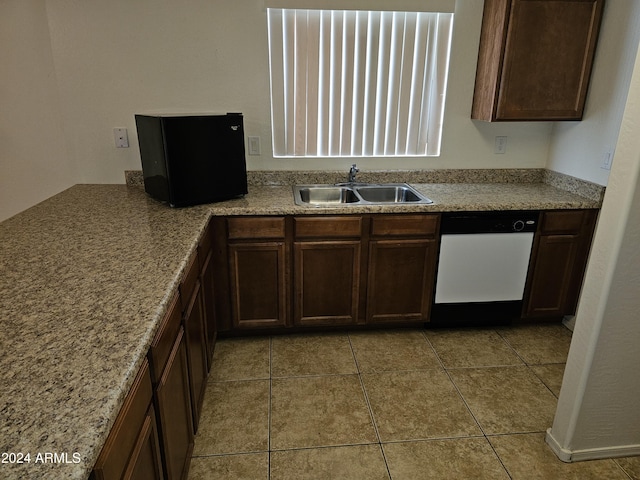 kitchen featuring dishwasher, light tile patterned flooring, dark brown cabinets, and sink