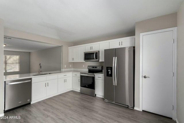 kitchen featuring appliances with stainless steel finishes, light countertops, a sink, and white cabinetry