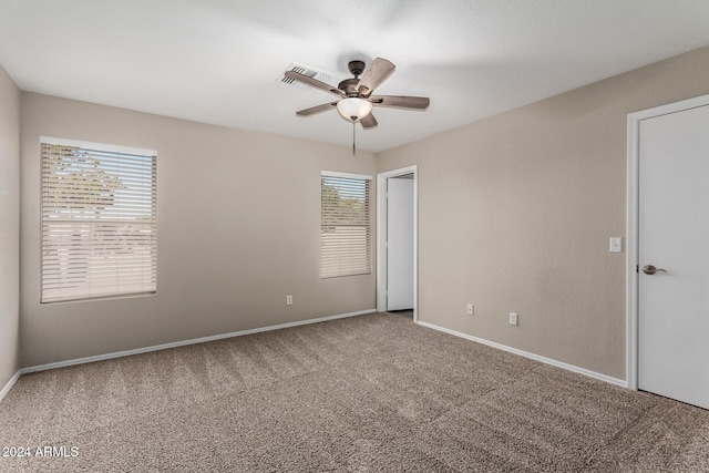 empty room featuring a wealth of natural light, carpet floors, and ceiling fan