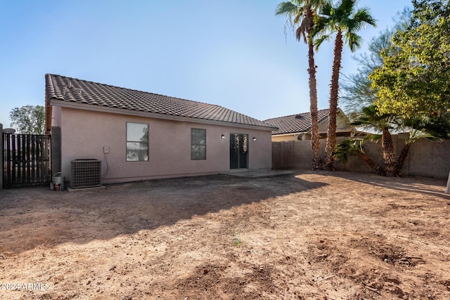 rear view of house featuring cooling unit, a tile roof, a fenced backyard, and stucco siding