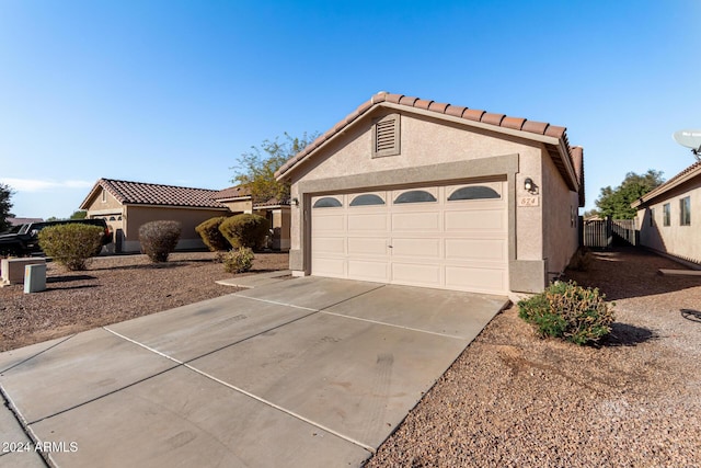 view of front of home featuring an attached garage, a tiled roof, concrete driveway, and stucco siding