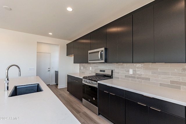 kitchen with sink, backsplash, light wood-type flooring, and appliances with stainless steel finishes