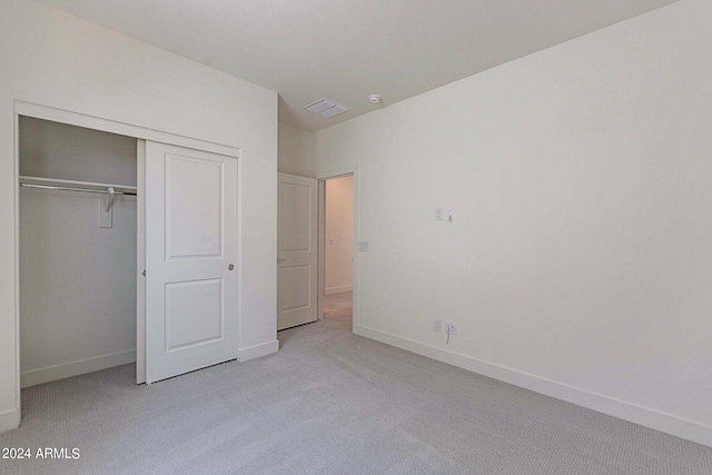 unfurnished bedroom featuring light carpet and a closet