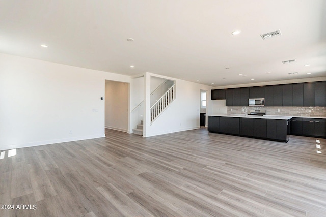 unfurnished living room featuring sink and light hardwood / wood-style floors