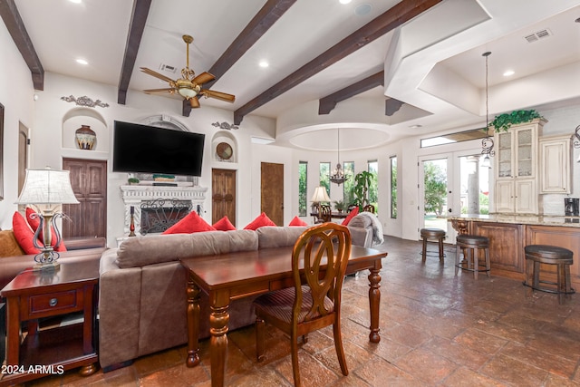 living room featuring beam ceiling and ceiling fan with notable chandelier