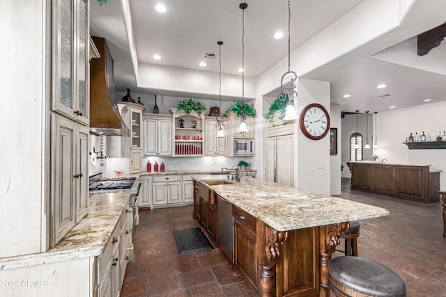 kitchen featuring a kitchen breakfast bar, wall chimney exhaust hood, sink, a large island with sink, and stainless steel microwave