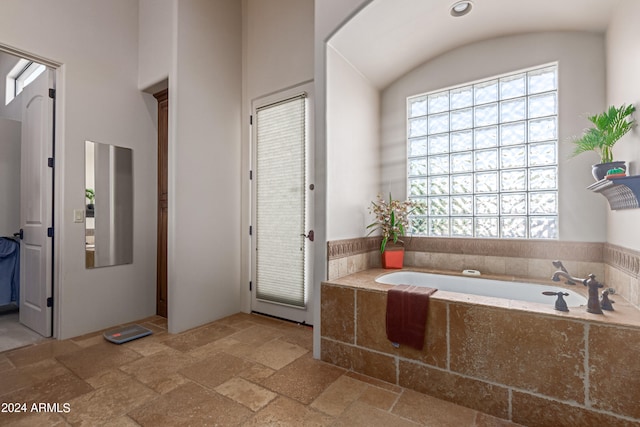 bathroom with tiled bath and lofted ceiling