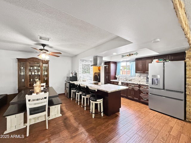 4639 W Keim Dr, Glendale, AZ 85301 - kitchen featuring fridge with ice dispenser, island exhaust hood, a breakfast bar area, light wood-type flooring, and a peninsula