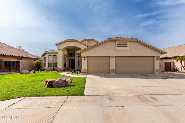 mediterranean / spanish house featuring a front lawn, fence, stucco siding, a garage, and driveway