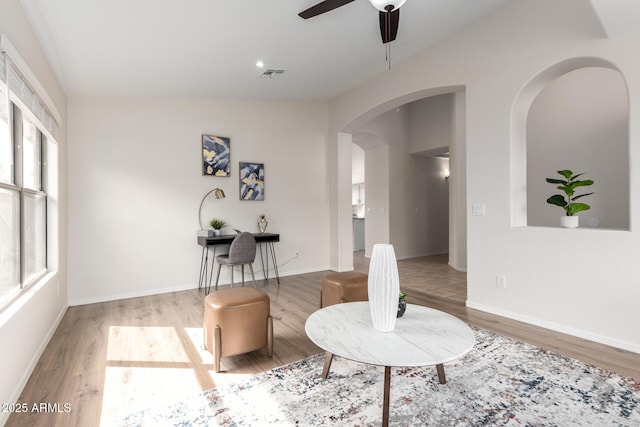 interior space featuring visible vents, baseboards, wood finished floors, arched walkways, and a ceiling fan