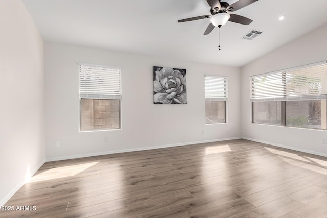 empty room featuring visible vents, baseboards, ceiling fan, vaulted ceiling, and wood finished floors