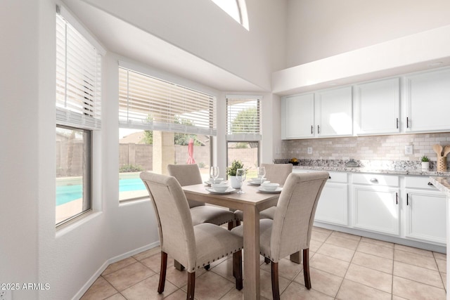 dining space with light tile patterned floors, baseboards, and a towering ceiling