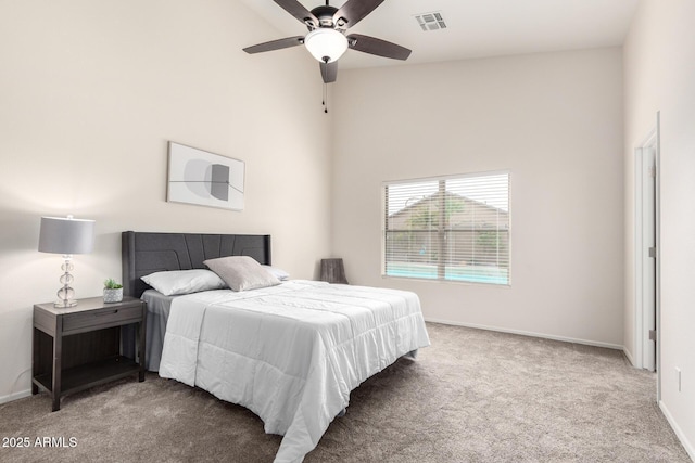 carpeted bedroom with a ceiling fan, baseboards, visible vents, and a towering ceiling