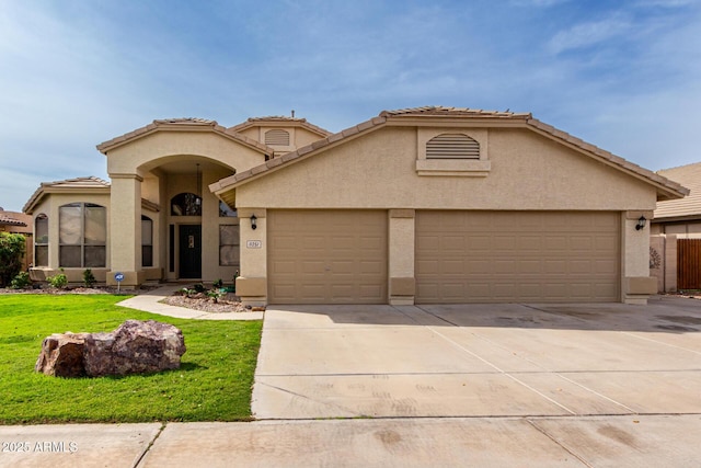 mediterranean / spanish house with a front yard, an attached garage, stucco siding, concrete driveway, and a tiled roof