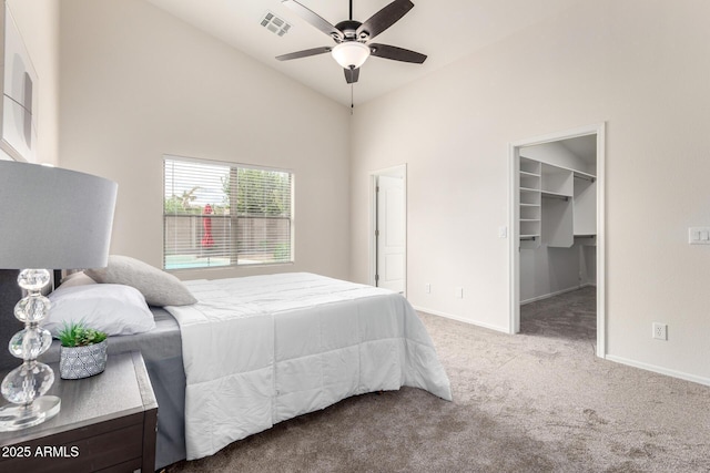 bedroom with visible vents, a walk in closet, baseboards, carpet floors, and high vaulted ceiling