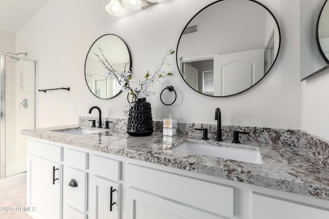 bathroom featuring a sink, a stall shower, double vanity, and tile patterned flooring