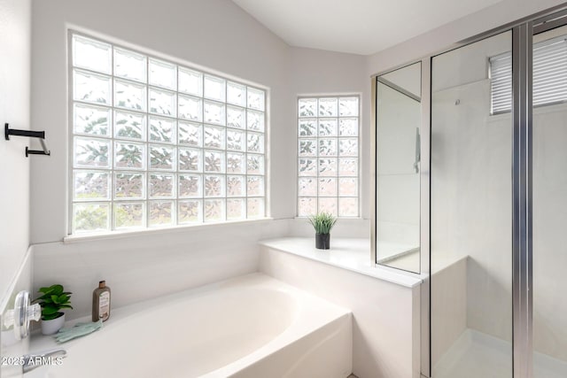 bathroom featuring a garden tub, a stall shower, and a wealth of natural light