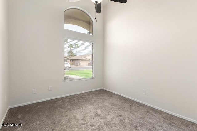 carpeted spare room featuring a ceiling fan and baseboards