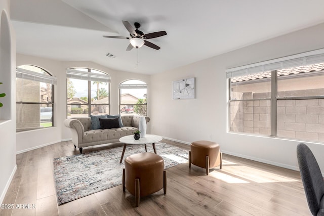 living room featuring a ceiling fan, wood finished floors, baseboards, visible vents, and lofted ceiling