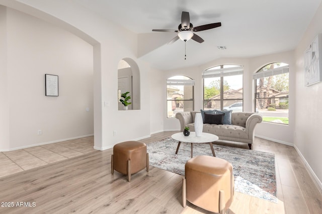 living room featuring visible vents, lofted ceiling, a ceiling fan, light wood finished floors, and baseboards