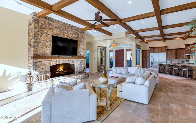 living room with coffered ceiling, a towering ceiling, a fireplace, and beamed ceiling